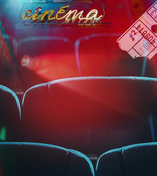 Kinosessel, eine Leuchtschrift "cinema" und eine abgerissene Kinokarte