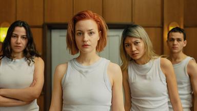 Vier junge Personen in weißen Tops schauen sehr skeptisch in Richtung Kamera.