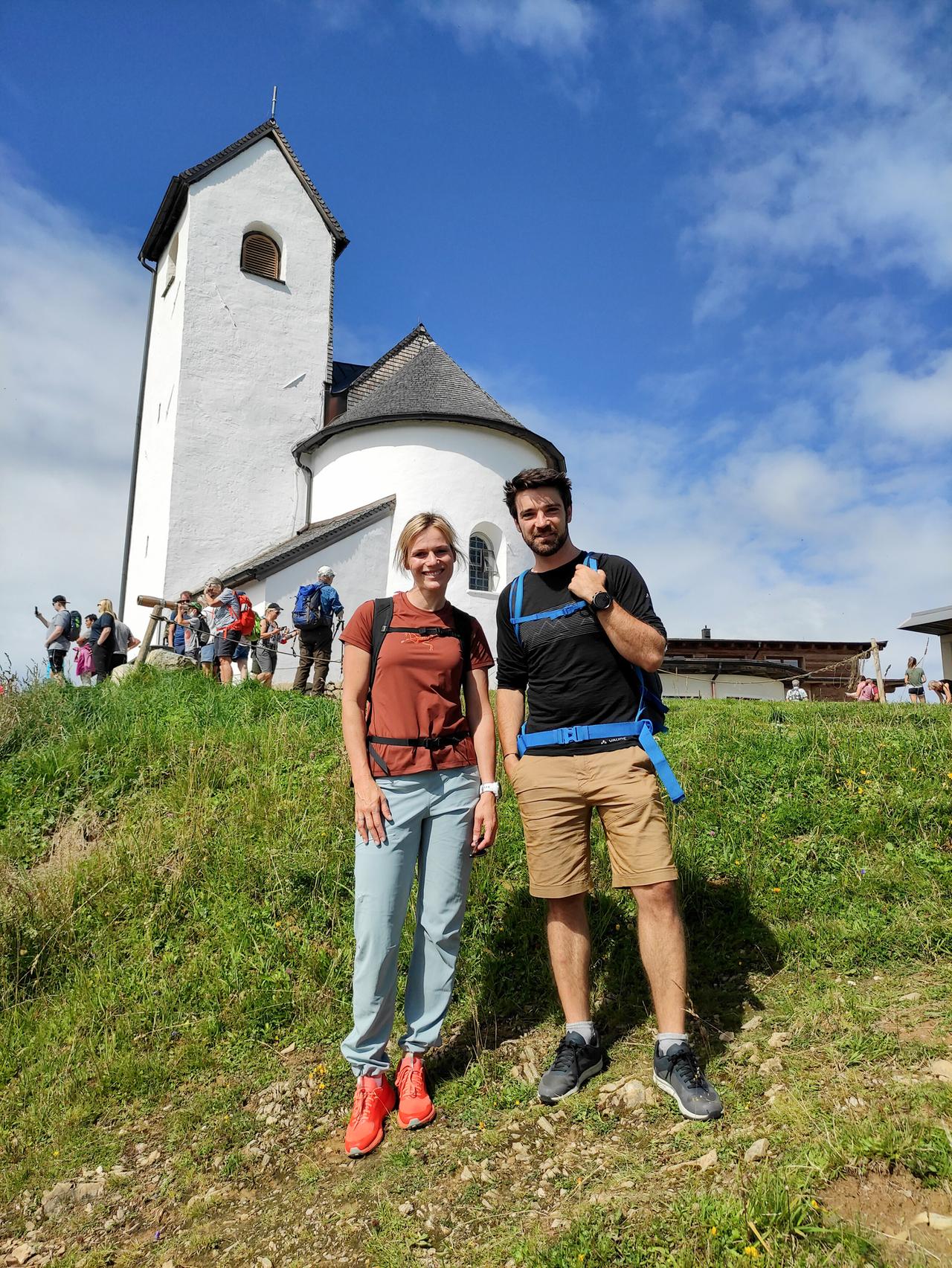 Frau und Mann in Wanderkleidung vor einer Bergkapelle