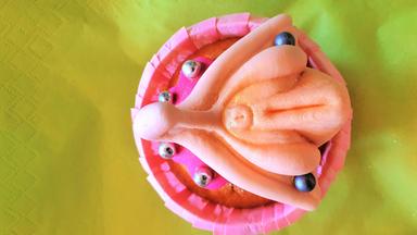 Ein Törtchen mit Zuckerguss in der Form einer Vagina mit Klitoris.