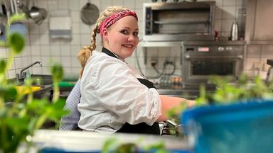 Eine junge Frau in einer Gastronomieküche.