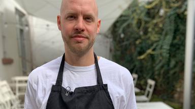 Ein Mann auf einer Gastronomieterrasse.