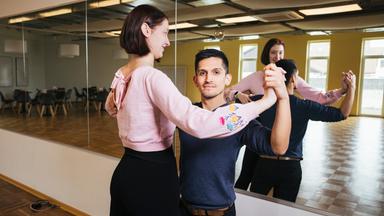 Tanzlehrer Federico Puma tanzt mit seiner Assistentin Sarah Weber in leerem Saal.