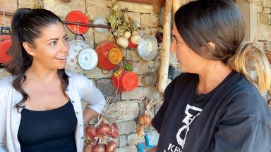 Serena Loddo (li.) steht an einer Wand mit Emaille-Sieben und unterhält sich mit Viviana Sirigu von der sardischen Bäckerei Kentos.