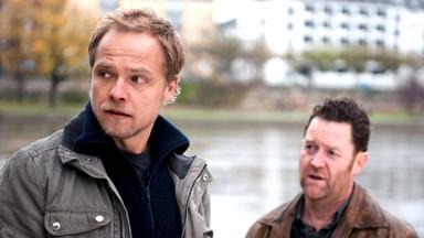 "Marthaler - Partitur des Todes": Robert Marthaler (Matthias Koeberlin) und sein Kollege Kai Döring (Jürgen Tonkel) stehen entsetzt am Ufer eines Flusses.