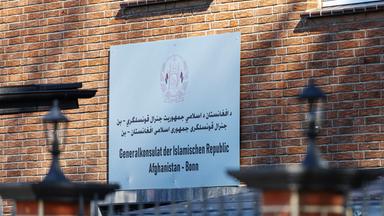 Ein Schild mit Informationen hängt an einer Hauswand.