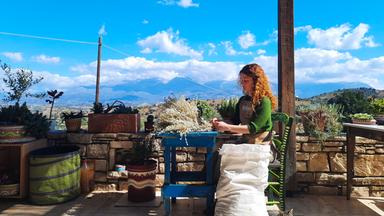 Eine Frau sitzt an einem kleinen Tisch und verpackt Teeblätter.