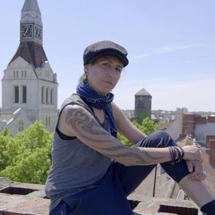 "Kültür für Deutschland“: DJ Ipek sitzt auf einem Dach in Berlin. Im Hintergrund sieht man die Stadt. 