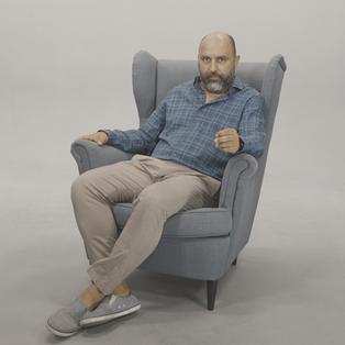 "Kültür für Deutschland“: Der Kabarettist Serdar Somuncu sitzt in einem grauen Sessel vor weißem Hintergrund. Er trägt ein kariertes Hemd und eine helle Hose.