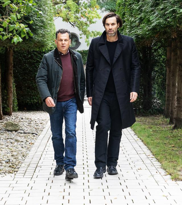 "Laim und die Toten ohne Hosen": Anton Simhandl (Gerhard Wittmann) und Lukas Laim (Max Simonischek) laufen nebeneinander einen Weg entlang.