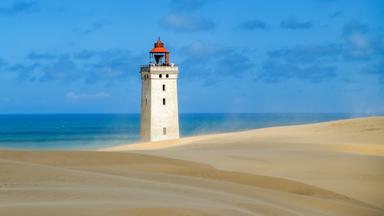 Ein Leuchtturm, umgeben von Sand und Meer
