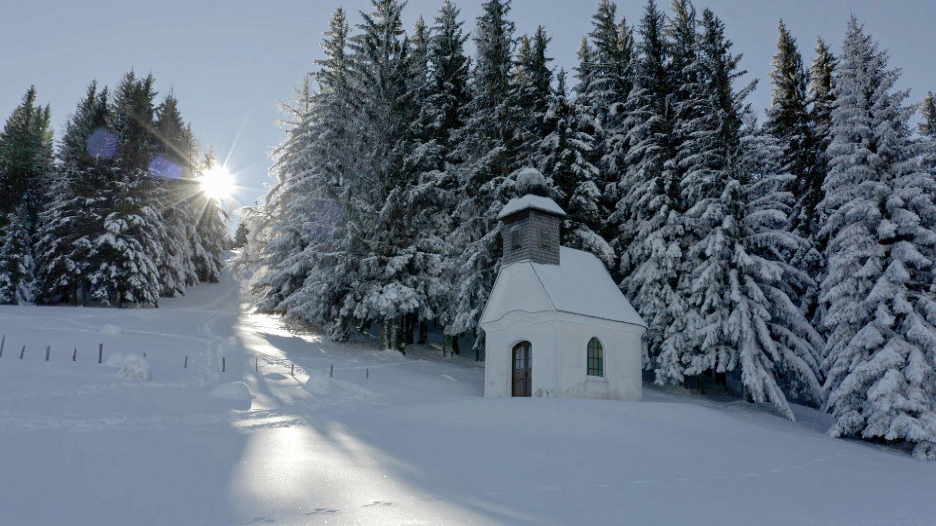 Kleine Kapelle in verschneiter Landschaft am Waldrand