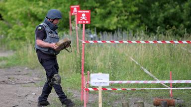 Ein Mann trägt eine Landmine auf dem Gelände einer Ziegelei, in der nach der russischen Besetzung noch viel Munition und andere explosive Gegenstände liegen. 