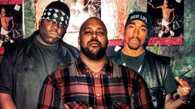 Drei Männer stehen zusammen, der Rapper Biggie Smalls, der Rapper Tupac Shakur und Suge Knight, Plattenboss, und zeigen den Mittelfinger.