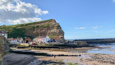 Steilküste von Staithes in North Yorkshire mit dramatisch aufragenden Klippen unter wolkenverhangenem Himmel.