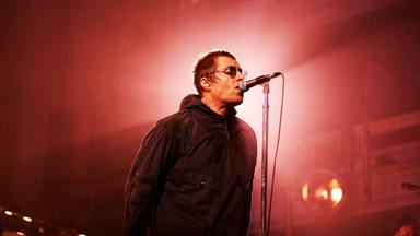 Liam Gallagher singt mit Sonnenbrille ins Mikro.