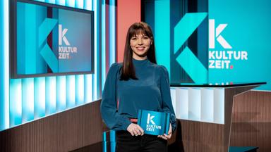 Die Moderatorin Lillian Moschen steht im Kulturzeit-Studio und hält eine Moderationskarte in der Hand.