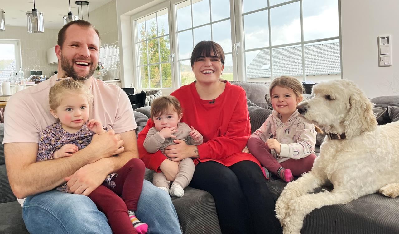 Familie Oelmüller mit drei Kindern und Hund auf dem Sofa.