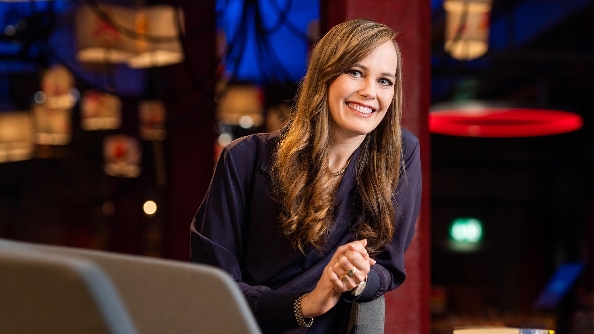 Die lächelnde Moderatorin Nicola Steiner seitlich über eine Armlehne gebeugt