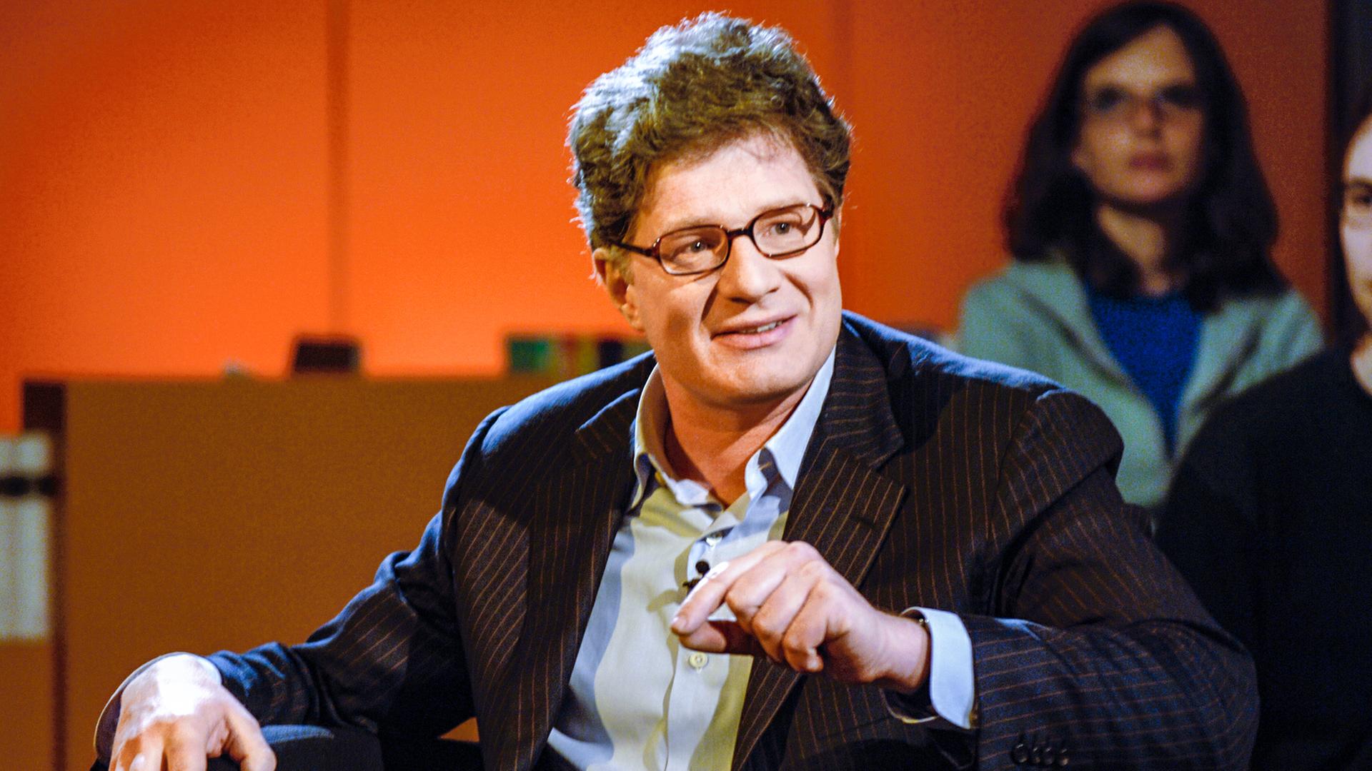 Moderator sprechend im Sessel