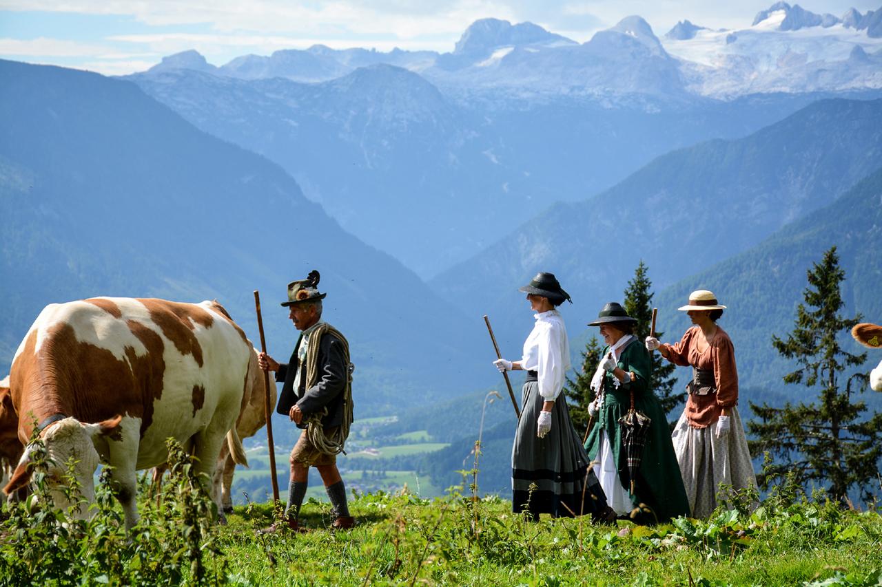 Mehrere Personen in historischen Kostümen und Kuh vor Bergkulisse