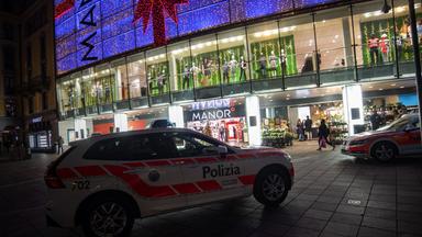 Ein Polizeiauto mit der Aufschrift Polizia steht vor einem weihnachtlich geschmückten Einkaufskomplex.
