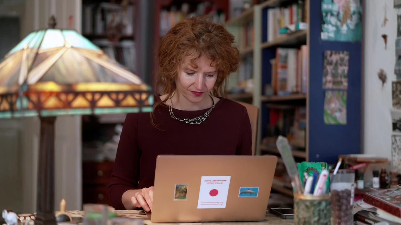 Frau sitzt am Schreibtisch und arbeitet am Computer
