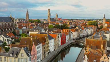 Blick von schräg oben auf Brügge, einer Stadt mit mittelalterlichen Gebäuden, durch die sich ein Kanal zieht.