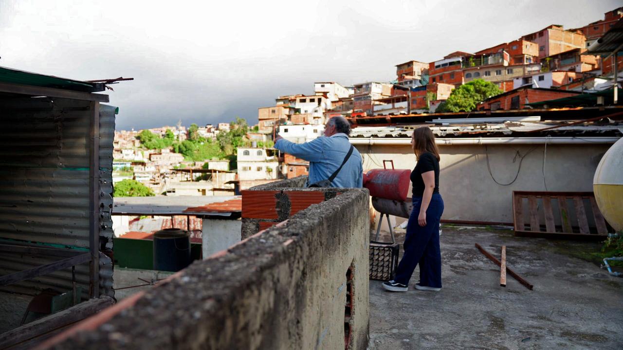 Ein Mann und eine Frau auf einer Terasse mit Blick auf ein Häuserviertel