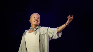 Mann steht auf einer Bühne und performt.