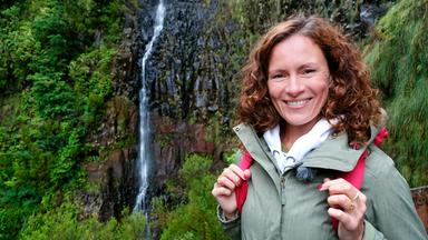 Eine Frau in Wanderausrüstung vor einem Wasserfall.