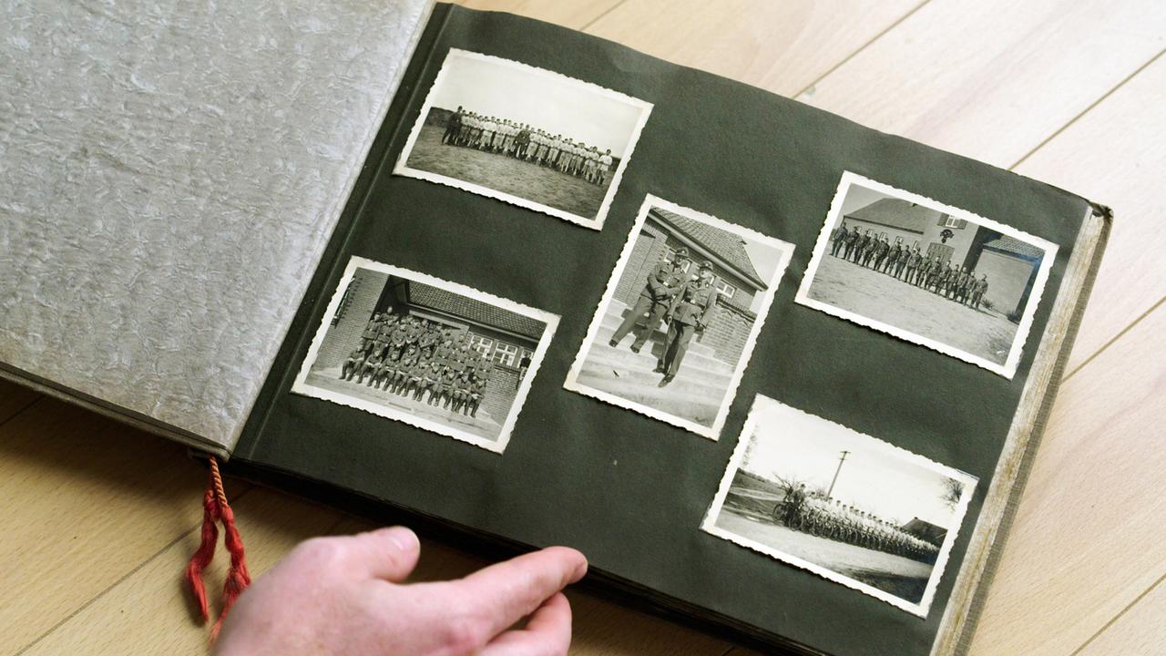 Ein aufgeschlagenes Fotoalbum mit fünf alten schwarz-weiss Fotos auf einer schwarzen Seite