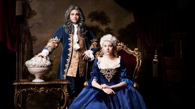 Ein Mann steht neben einer sitzenden Frau in blauer Robe.