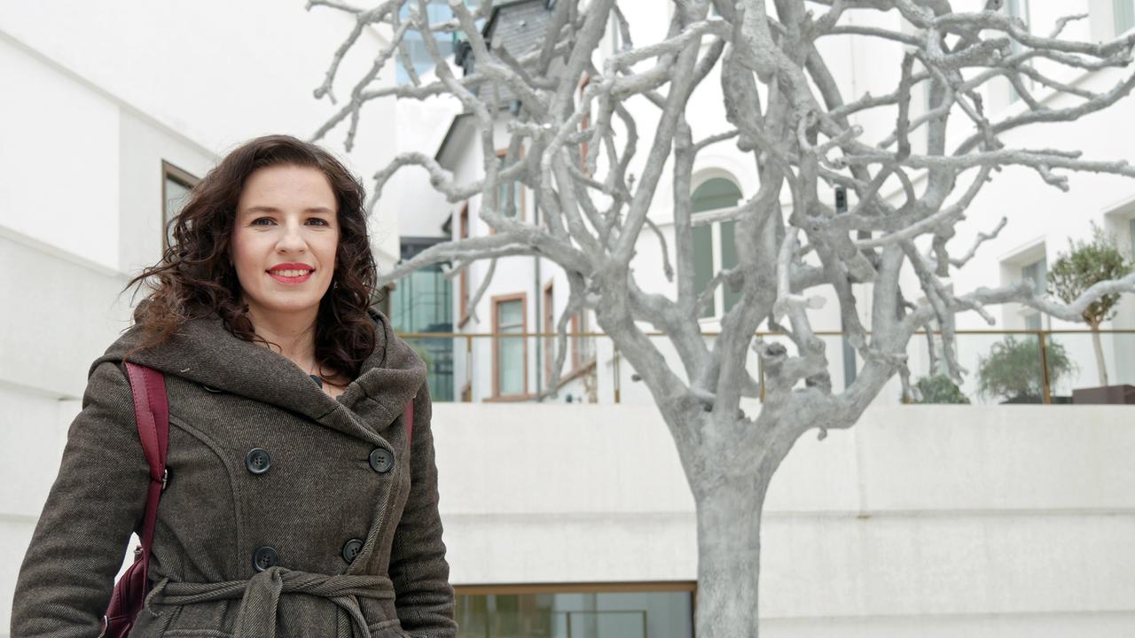 Eine Frau in Winterjacke vor einem skurrilen Baum im Hof des Museums.