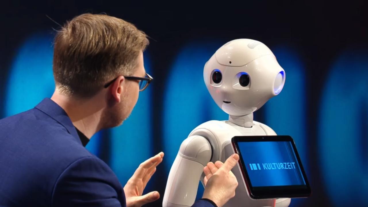 Markus Gabriel sitzt neben Roboter Pepper im Kulturzeit-Studio