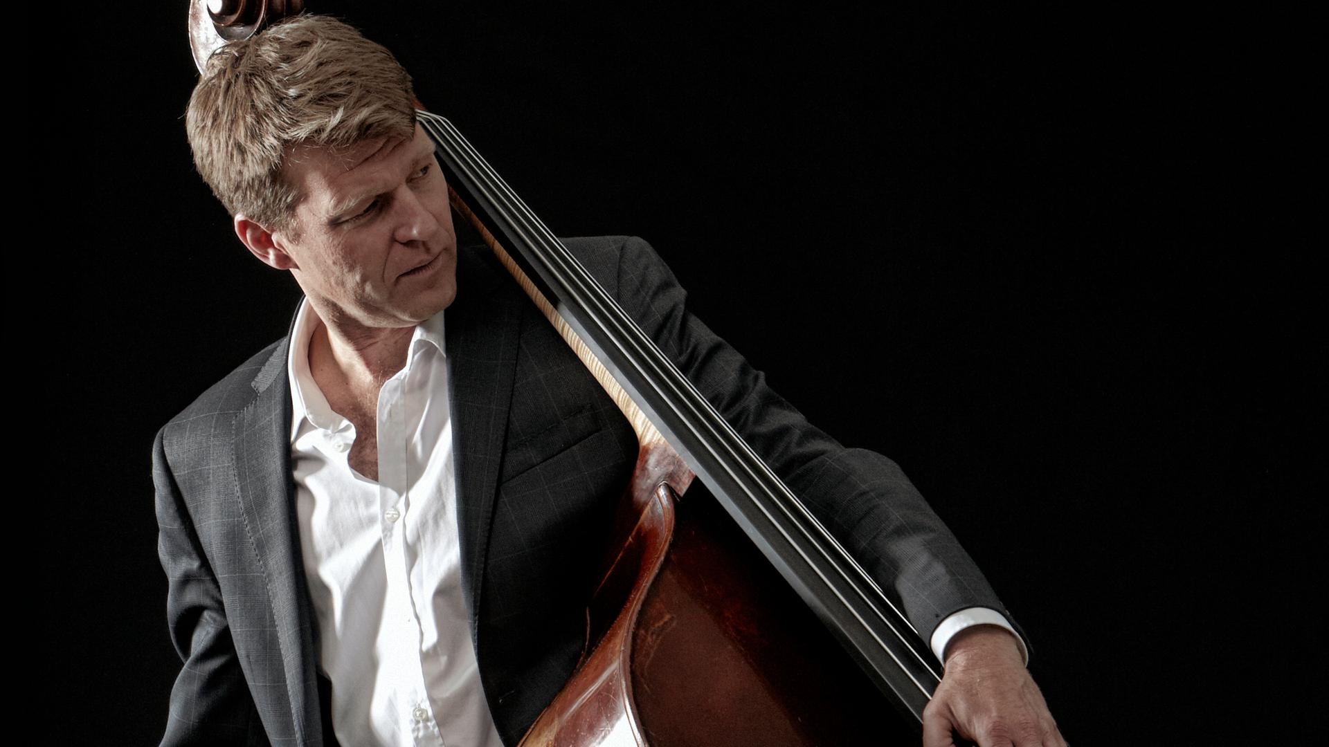 Der Bassist Martin Wind mit Kontrabass, seitlich den Kontrabass auf der Hüfte tragend.