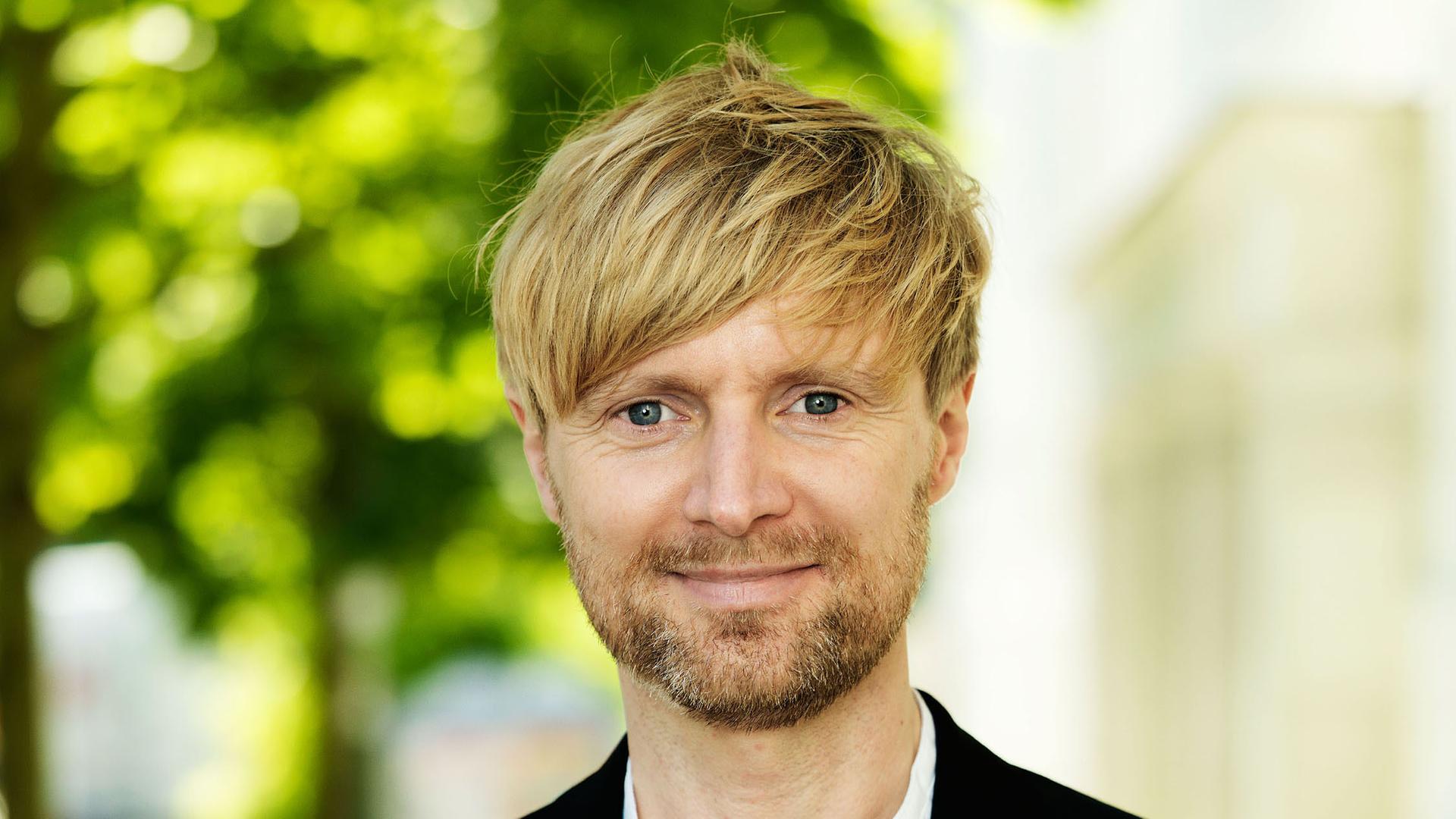 Ein junger Mann mit blondem Haar und Anzug.