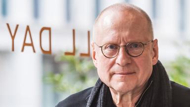 Porträtfoto eines Mannes mit Glatze und runder Brille.