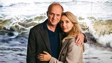 Ein Mann und eine Frau, Arm in Arm am Meer.