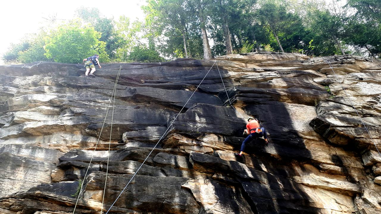 Frauen an einer Steinwand an Seilen.