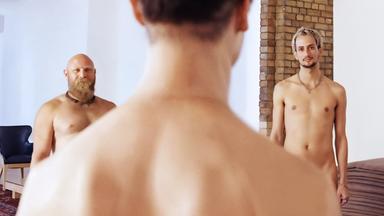 Nackte Männer stehen in einem Kreis.