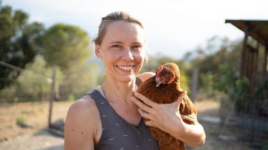 Eine Frau hält ein Huhn im Arm.