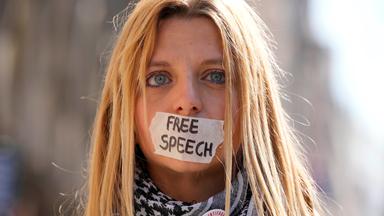 Eine Fau mit einem, mit Klebeband, zugeklebten Mund, mit der Aufschrift "Free Speech".