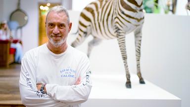 Ein Mann vor der Statue einer Giraffe.