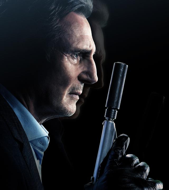 Liam Neeson hält eine Waffe mit Schalldämpfer in der behandschuhten Hand.