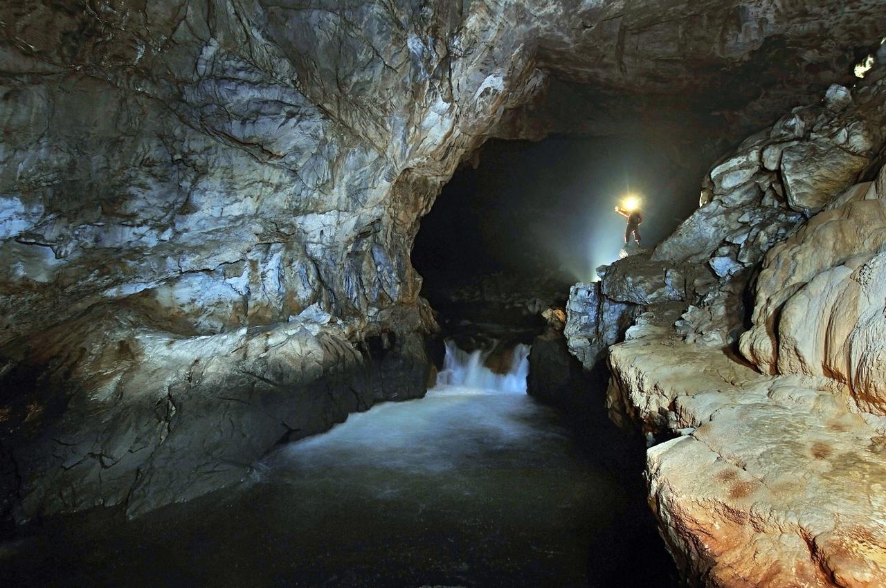 Ein Mann steht unter Tage an einem unterirdischen Fluss