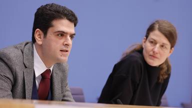 Mann und Frau sitzen an Tisch.