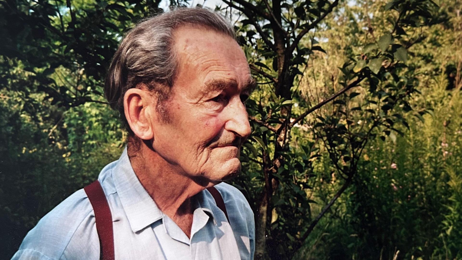 Seitliche Nahaufnahme vom Kopf eines alten Mannes in einem Garten.