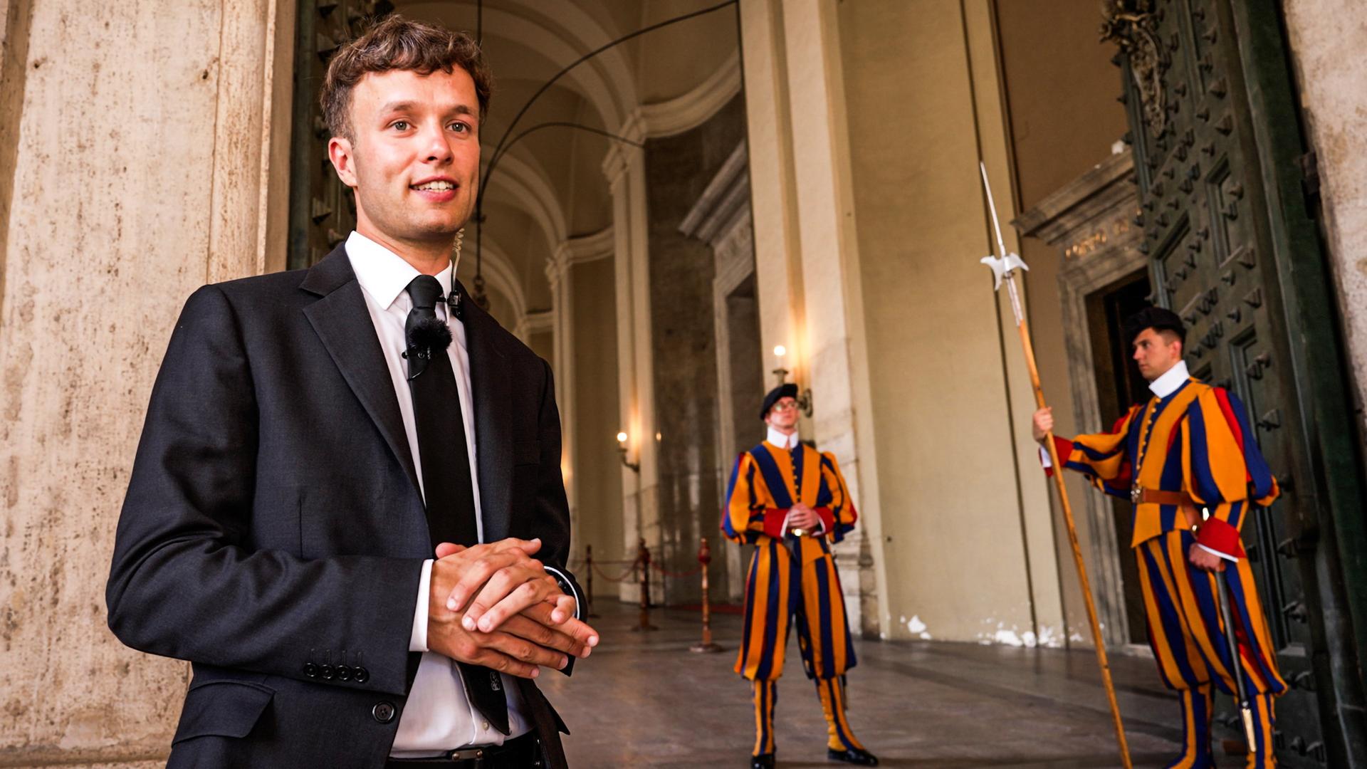 Ein Mann in Uniform der Schweizergarde steht vor einer historischen Kulisse. 