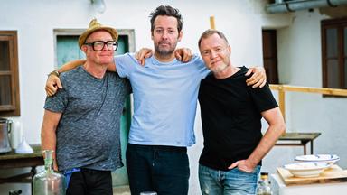 Drei Männer in lässigem Outfit vor einem Käsebrett